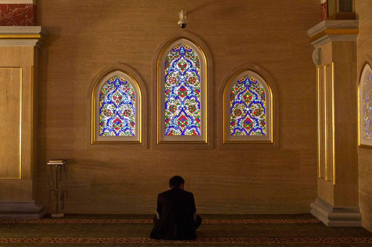 Мужчина молится в мечети